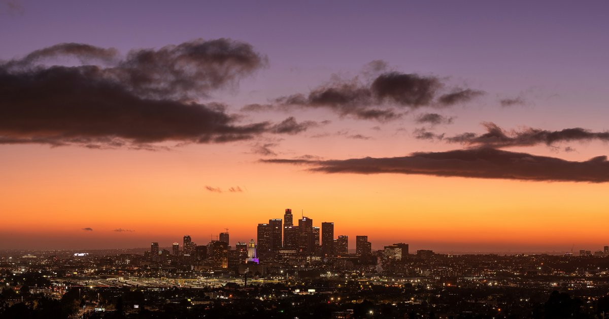 Panoramic Los Angeles cityscape at dusk viewed from the hills, showing the dense basin lights below, representing the kind of dramatic view photography that is commonly enhanced in luxury listing photos