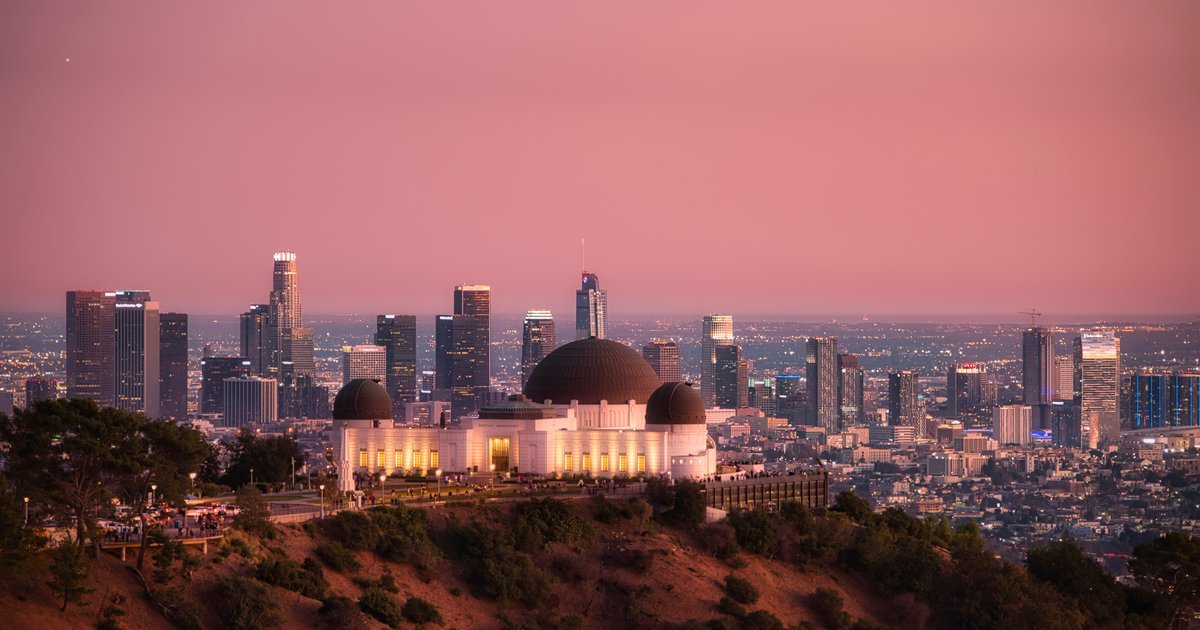 Griffith Observatory lit at dusk on a hillside with the Los Angeles skyline behind it