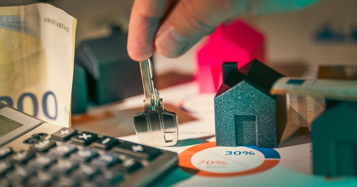 A hand holding a house key over several miniature home models, representing the bridge loan process that lets DFW move-up buyers purchase a new home before their current one sells