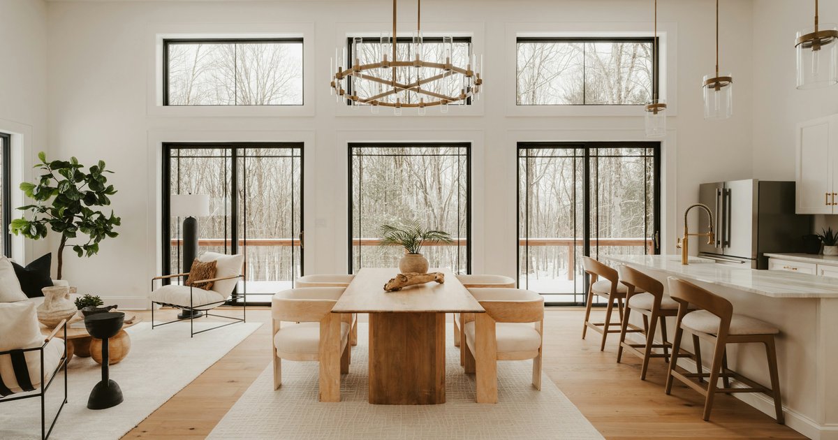 A modern open-plan living and dining area in a newly built home with large windows and light finishes