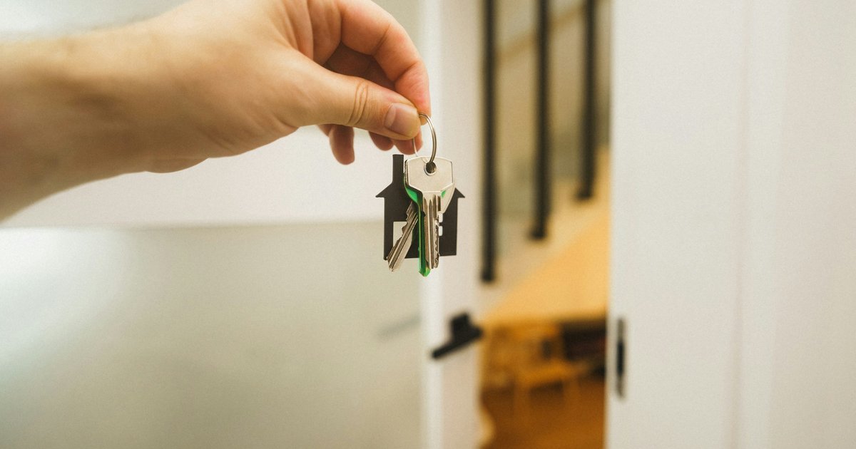 A hand holding a key to a door, representing the real estate closing process and seller obligations in California