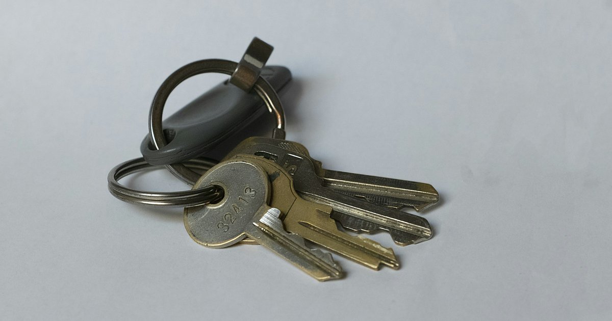 A house key resting on a stack of folded documents on a polished wood desk, representing the title and closing paperwork involved in a Texas cash home purchase