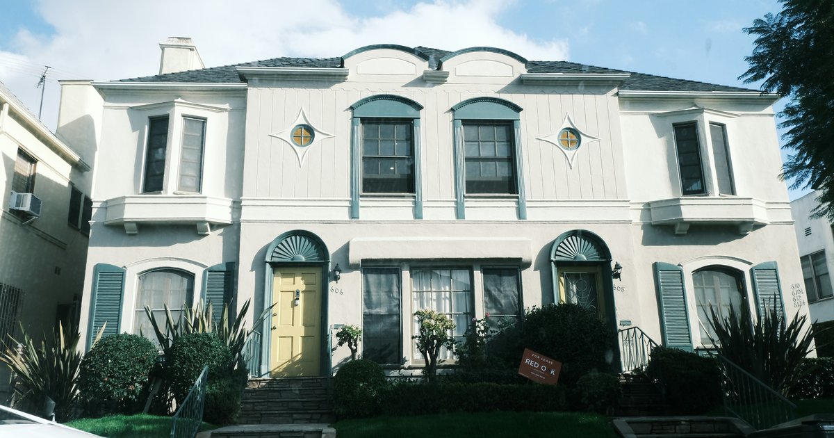 A white house with green shutters and a yellow front door