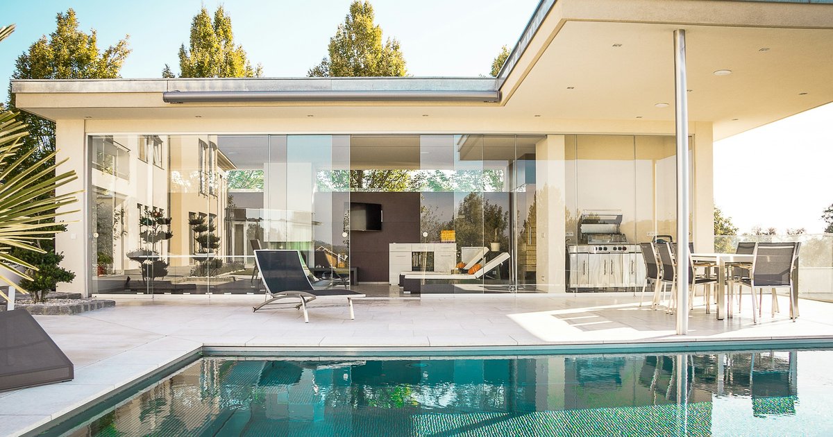 A modern glass-walled luxury home with an outdoor pool, representing the high-value properties where earnest money deposits run $100,000 or more in the Los Angeles market
