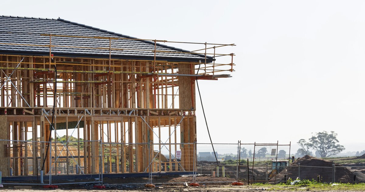 A two-story house frame with scaffolding, the stage a build-to-order home passes through before move-in