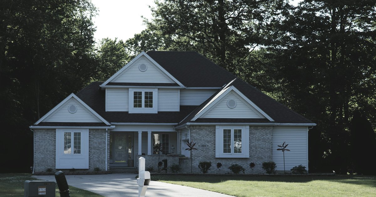 A modern suburban home with a green lawn and mature trees, representing a family property being considered for a gift of equity transfer