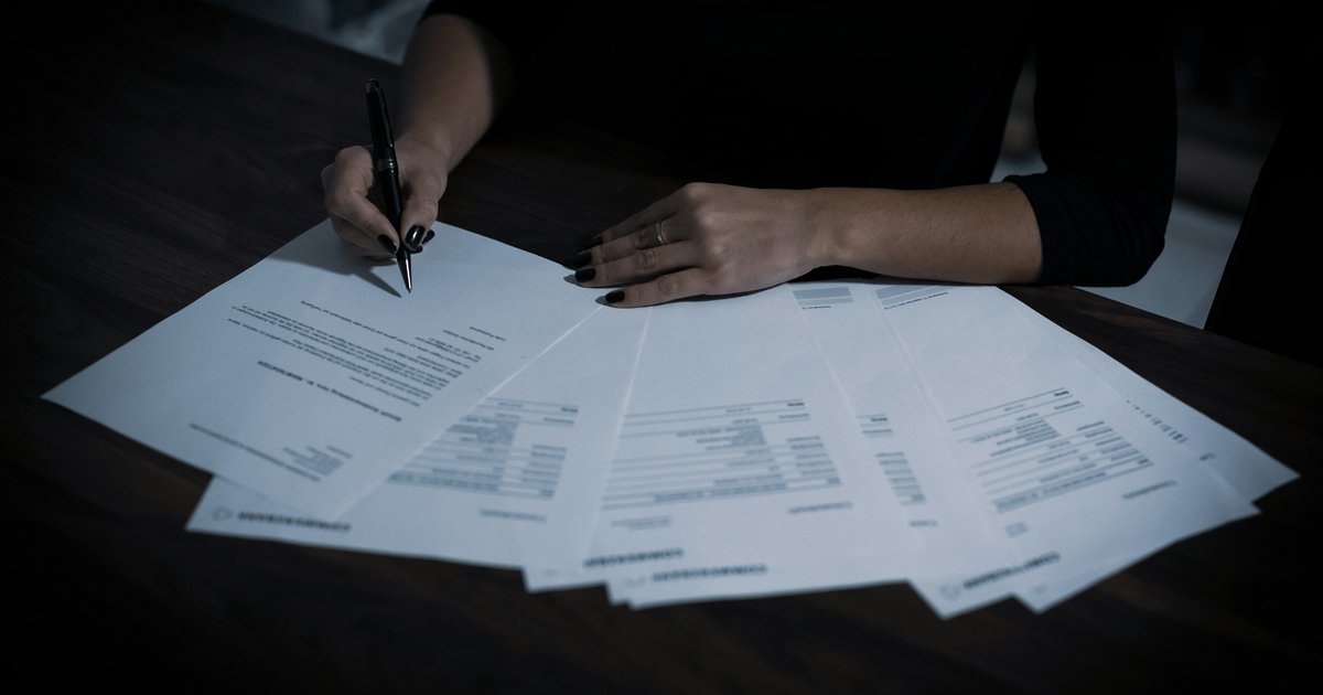 A notary reviewing real estate closing documents with a pen resting on signature pages