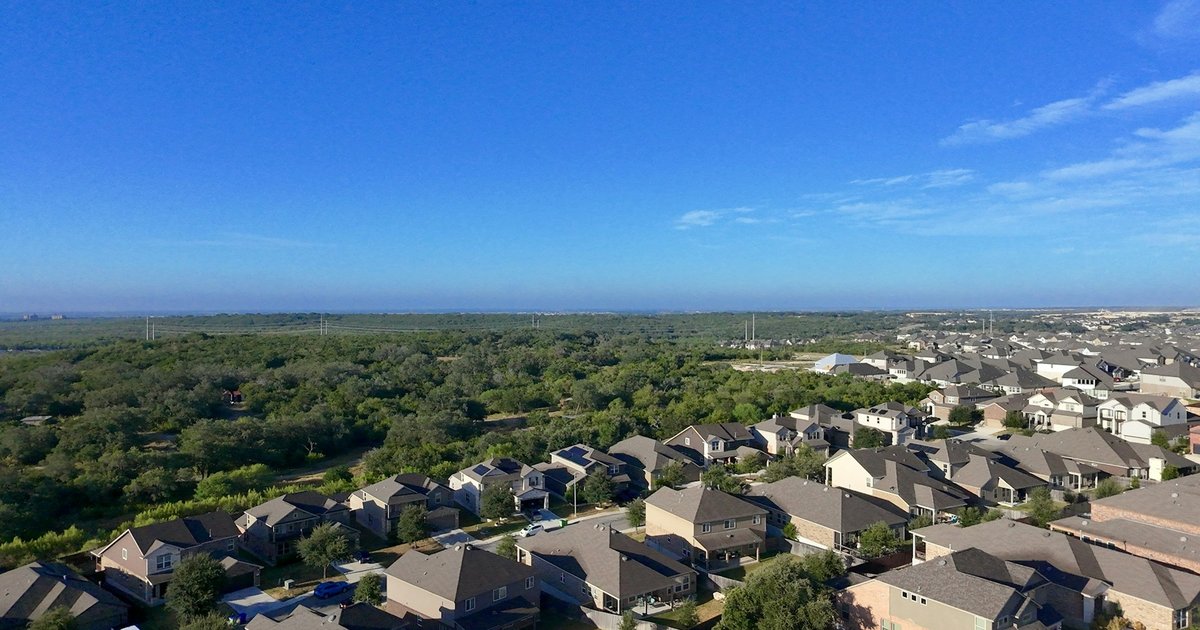 New-construction homes on curving streets beside a wooded greenbelt, representative of the planned-community streetscape found across eastern Collin County