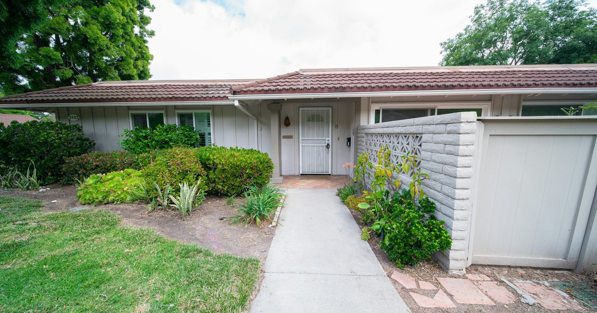Single-story Los Angeles home with a tile roof, white front door, and a concrete walkway running past low garden planting to the sidewalk