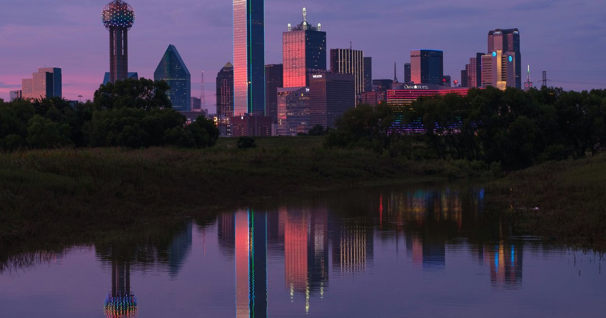 Dallas skyline at dusk reflected in still water, a stock photograph of the city the M Streets sit just northeast of