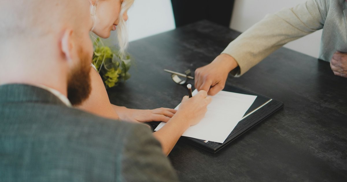 A California real estate agent reviews a purchase agreement with clients at a conference table