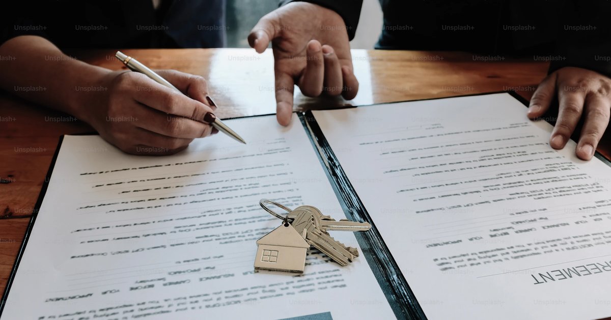 A person signs a contract document with a set of house keys resting on the page, representing the TREC Amendment to Contract process in a Texas real estate inspection negotiation