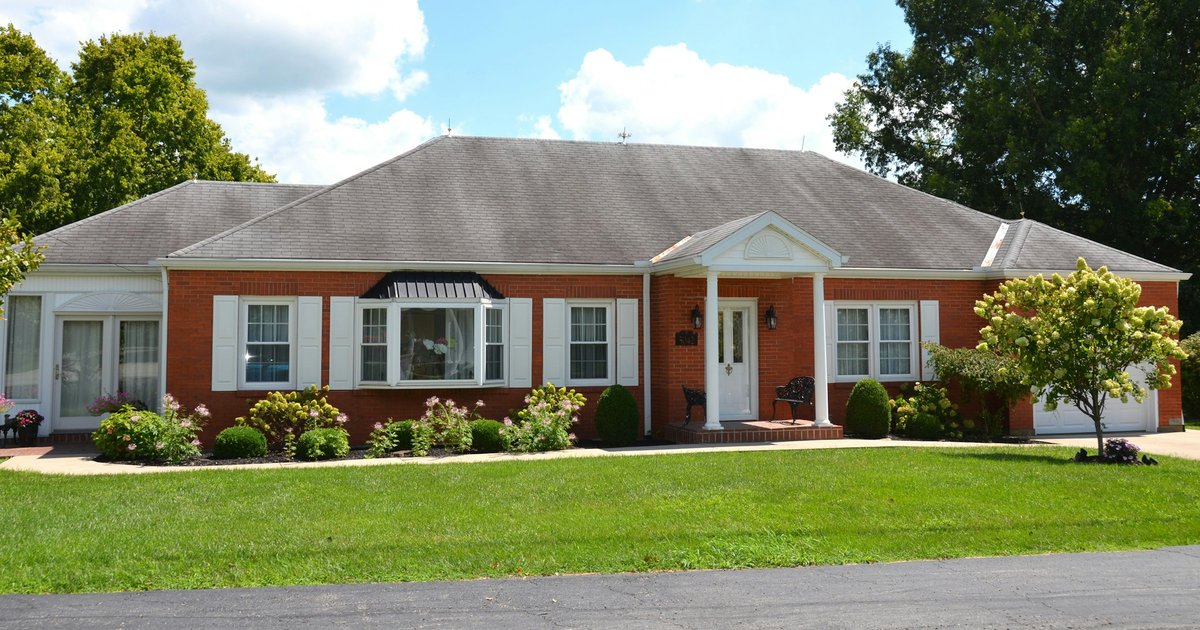 Single-story red brick ranch house with white shutters, a front portico and a bay window, illustrating the one-story brick style common in older Dallas neighborhoods