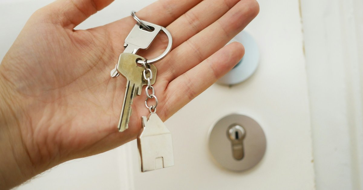 A set of keys in hand representing the moment of a real estate transaction — the listing strategy you choose determines who gets to make that handoff
