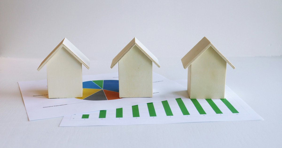 Three small house models sitting on top of a piece of paper, representing property tax calculations and closing costs