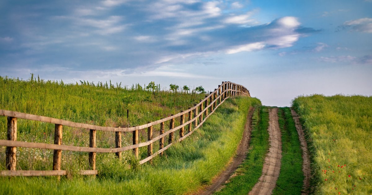 Wooden fence running across an open grassy field