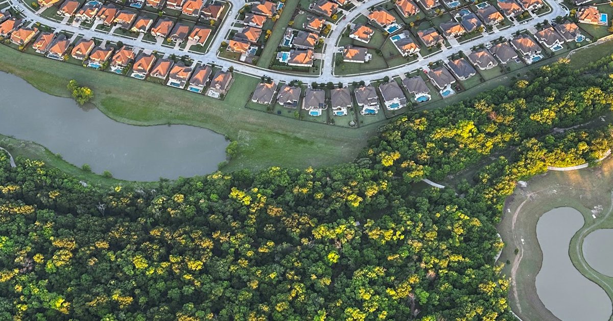 Aerial view of a suburban neighborhood bordering green space near Denton County
