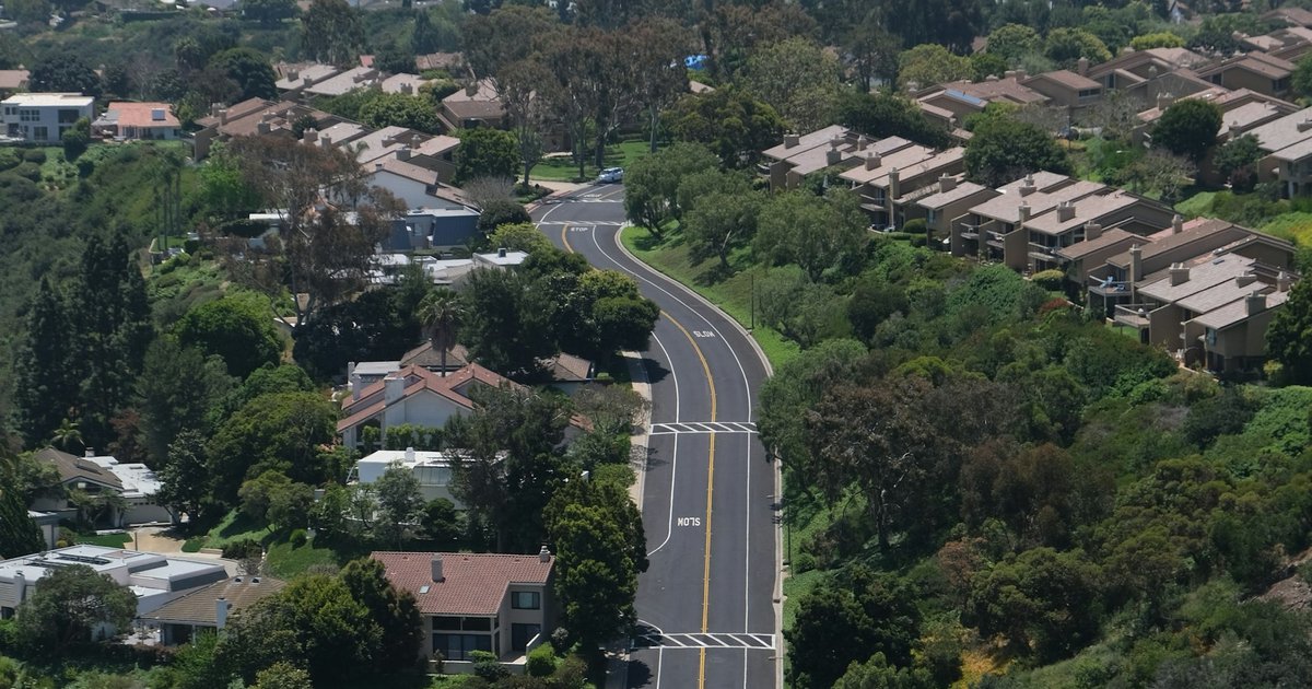 A canyon road lined with oak and chaparral descending toward the coast in the Santa Monica Mountains foothills near Pacific Palisades