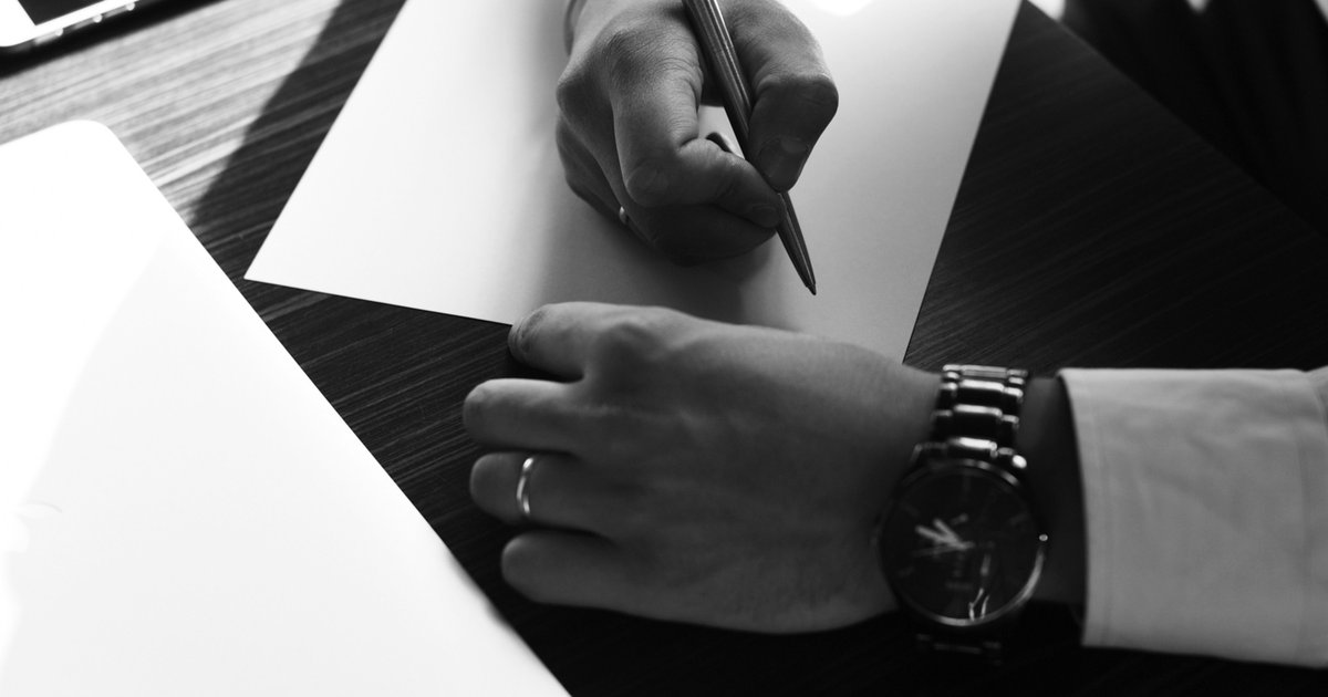 Person reviewing a real estate contract at a desk, with documents spread out and a pen in hand