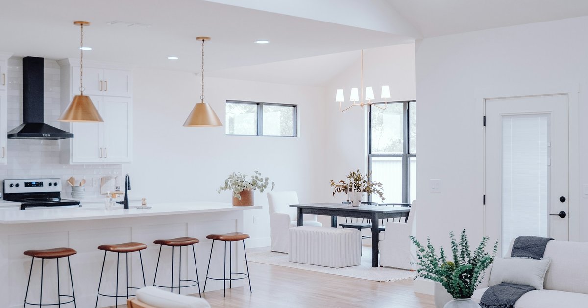 A bright open kitchen and dining area in a new-construction home, with pendant lights and a white island