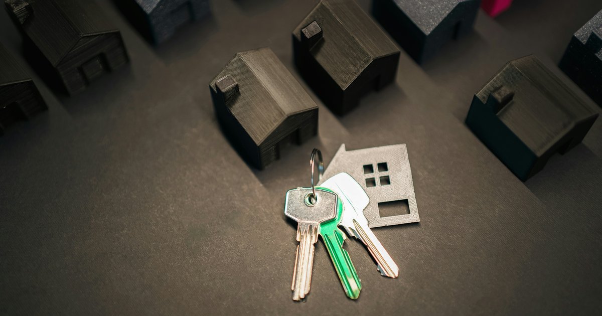 Two sets of keys on a wooden table beside a real estate contract, representing co-ownership of a property