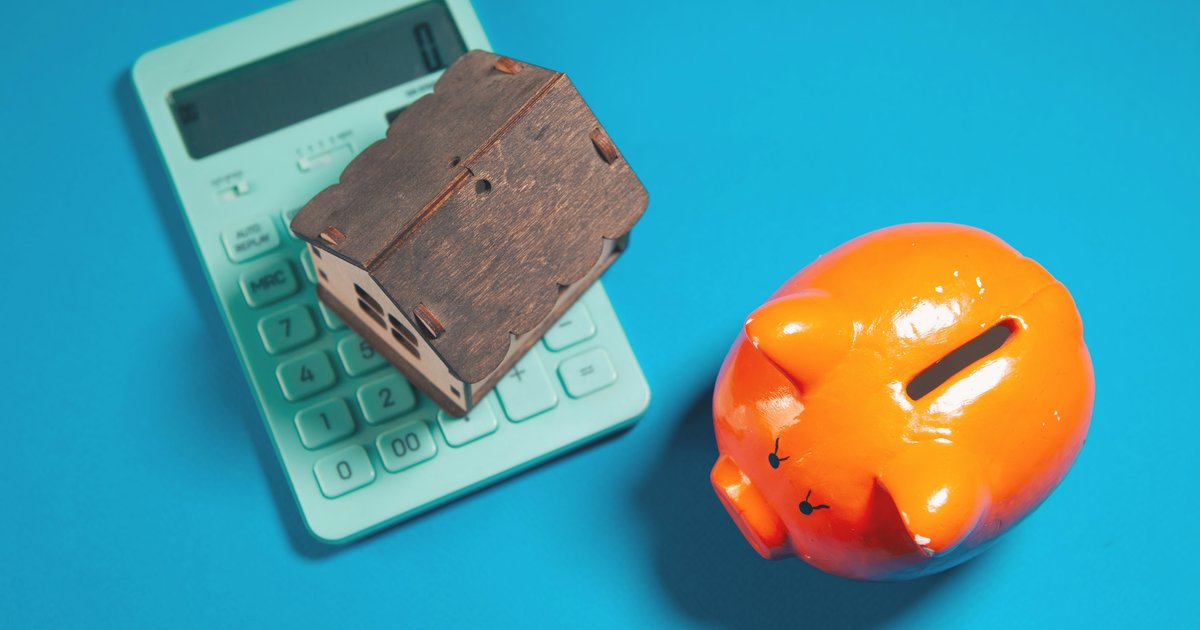 A miniature house model next to a calculator and piggy bank, illustrating the monthly savings math behind a VA IRRRL refinance