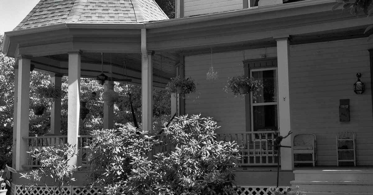 A front porch with wide columns, a hanging planter, and a hipped roof, representative of the porch-forward architecture found in historic Dallas neighborhoods